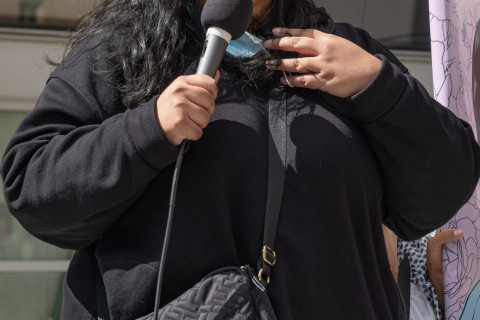 Demonstrator with long black hair and dressed in black at mic