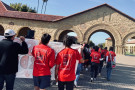 view from rear...students in red t-shirts march near iconic stanford arch