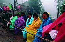 Mujeres zapatistas sentadas detrás de una marca del territorio zaptatista en Polhó, Chiapas, Mexico.