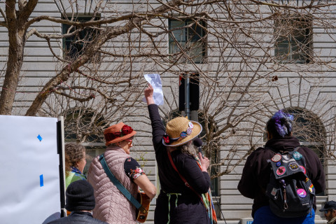 Backs of women with hats leading cheers with raised arm