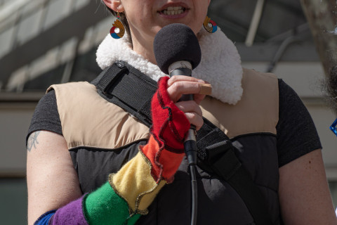 Protester with rainbow colored long gloves at the microphone
