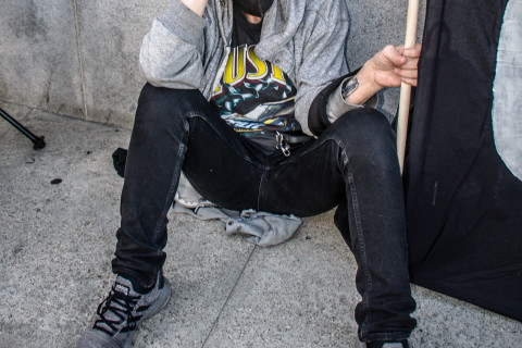 Lone demonstrator looks tired sits on ground