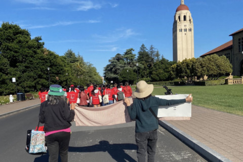 iconic Hoover tower is in view as elderly women shown from rear of march