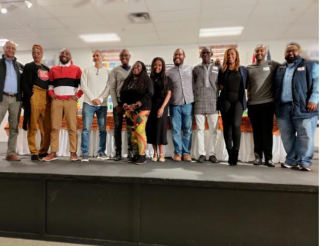 Black people standing together in line on a stage, posing for a photo