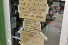 A photo of Firestorm Books' front door. Cardboard signs taped to the glass.