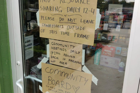 A photo of Firestorm Books' front door. Cardboard signs taped to the glass.