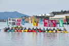 Kayaks sail with banners, flags and shouts that say “No Coal Coast to Coast,” “We’re Still Watching,” “Fossil Free Future for All,” “Newc...