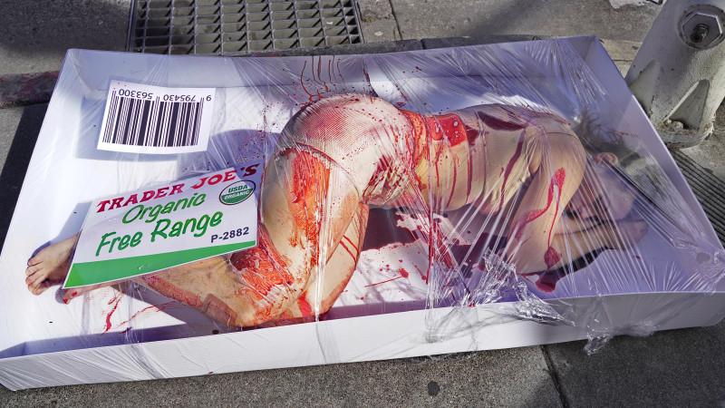 An activist covered in fake blood lies in a “human meat” display outside Trader Joe’s in Berkeley on March 1st, 2025, as protestors insid...