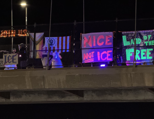 Blacklight protest banners on University Ave bridge