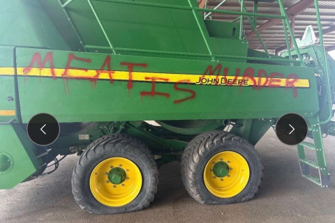 Large tractor with flat tires and "Meat Is Murder" spraypainted on it