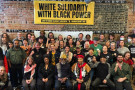 A group of about sixty people assembled under a banner that reads "White Solidarity with Black Power."